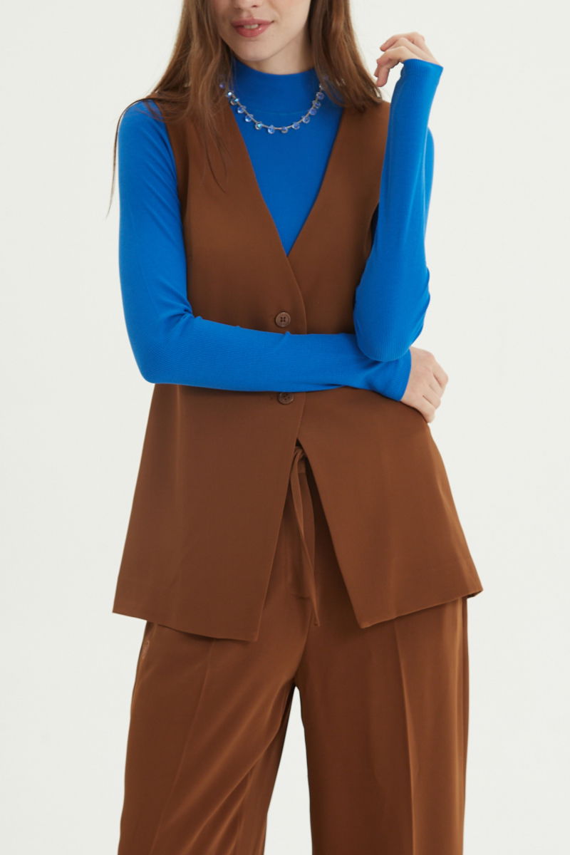 Chaleco sastrero suela con escote en V y largo a la cadera con botones a tono y lazo en la espalda. 