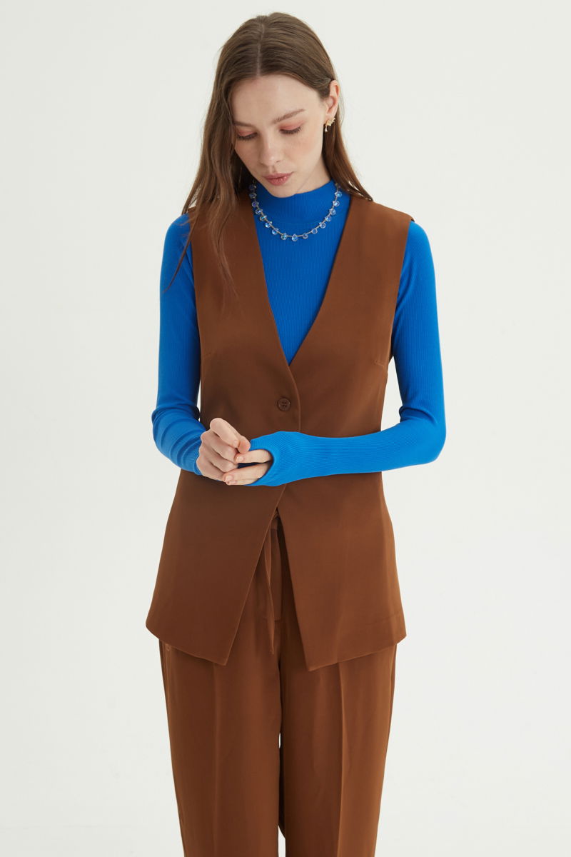 Chaleco sastrero suela con escote en V y largo a la cadera con botones a tono y lazo en la espalda. 