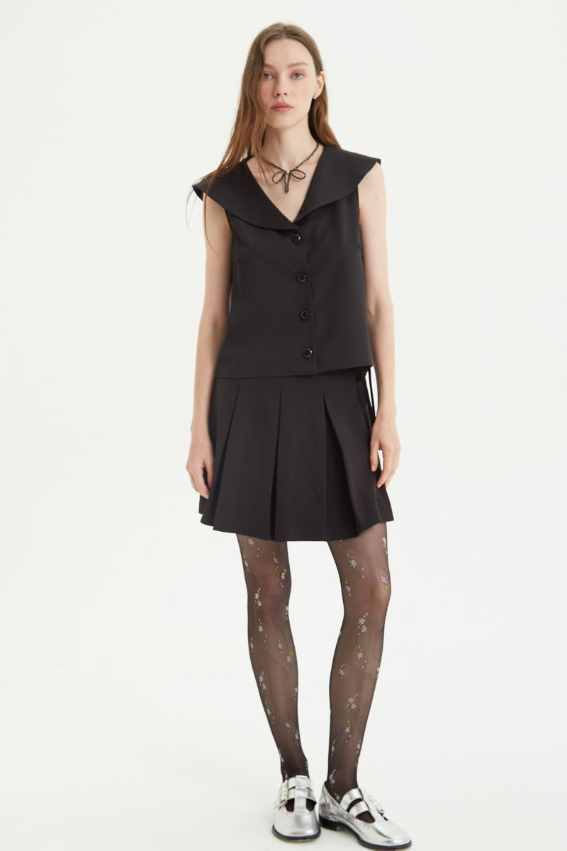 Falda negra sastrera acampanada con sobre falda tableada con lazo para atar en el lateral. 