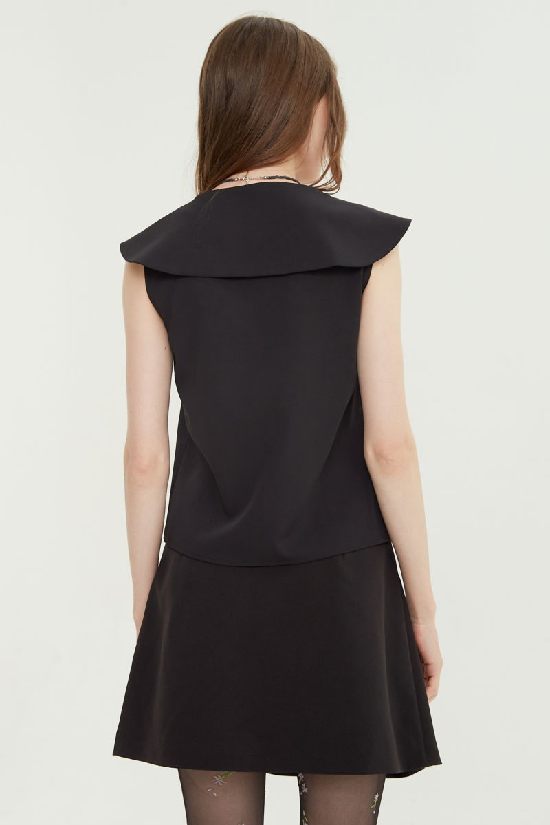 Falda negra sastrera acampanada con sobre falda tableada con lazo para atar en el lateral. 