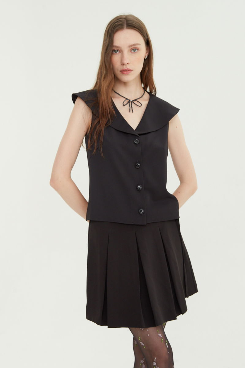 Falda negra sastrera acampanada con sobre falda tableada con lazo para atar en el lateral. 