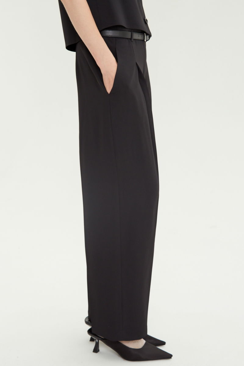 Pantalón negro sastrero tiro alto, de corte recto y largo hasta los tobillos con pinzas de entalle en frente y espalda. 