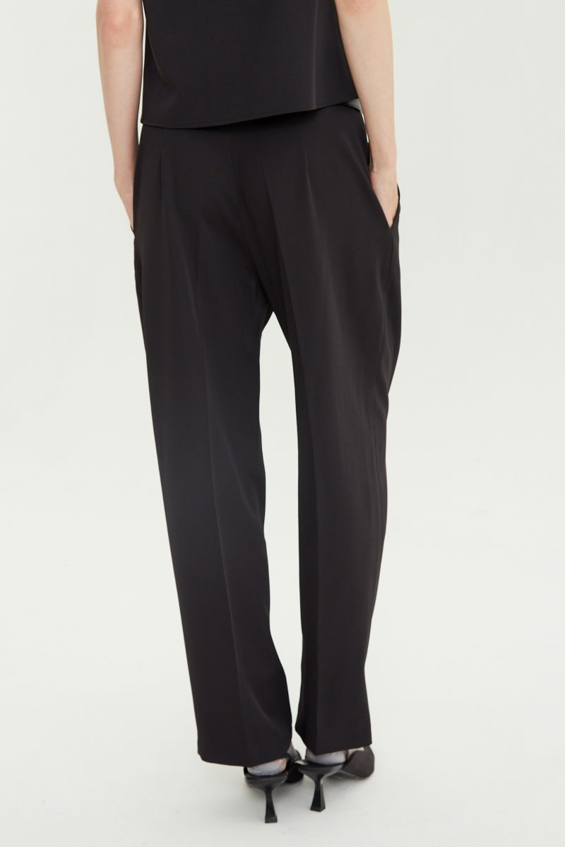 Pantalón negro sastrero tiro alto, de corte recto y largo hasta los tobillos con pinzas de entalle en frente y espalda. 