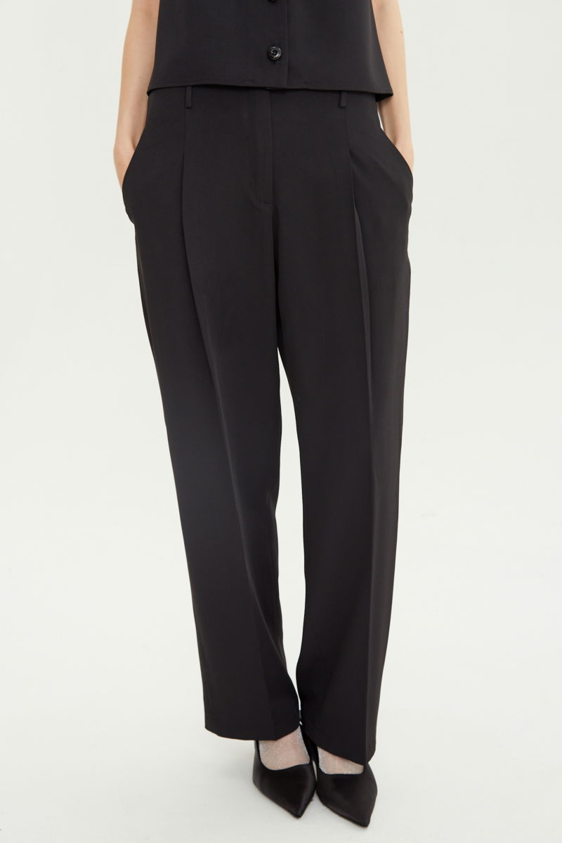 Pantalón negro sastrero tiro alto, de corte recto y largo hasta los tobillos con pinzas de entalle en frente y espalda. 