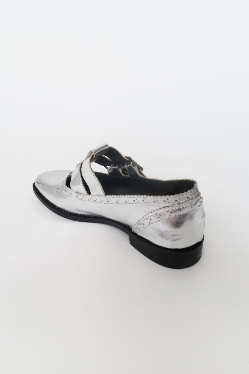 Guillermina de cuero metalizado con punta redonda y taco de 2 cm, con dos tiras ajustables con hebillas metálicas, detalles de zigzag y picado y vira marcada. 