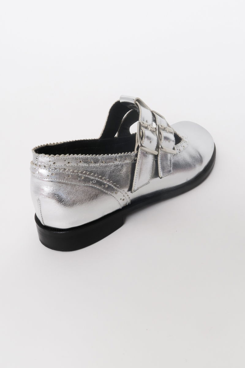 Guillermina de cuero metalizado con punta redonda y taco de 2 cm, con dos tiras ajustables con hebillas metálicas, detalles de zigzag y picado y vira marcada. 