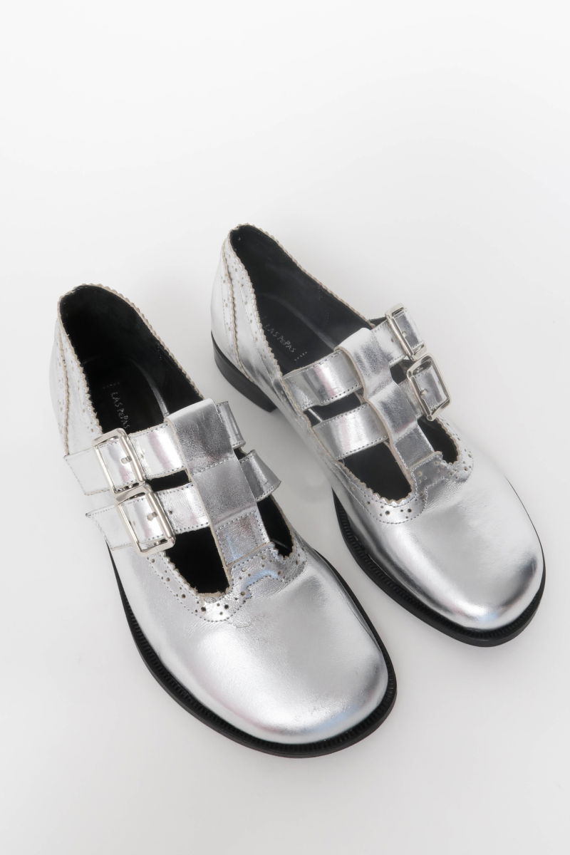 Guillermina de cuero metalizado con punta redonda y taco de 2 cm, con dos tiras ajustables con hebillas metálicas, detalles de zigzag y picado y vira marcada. 