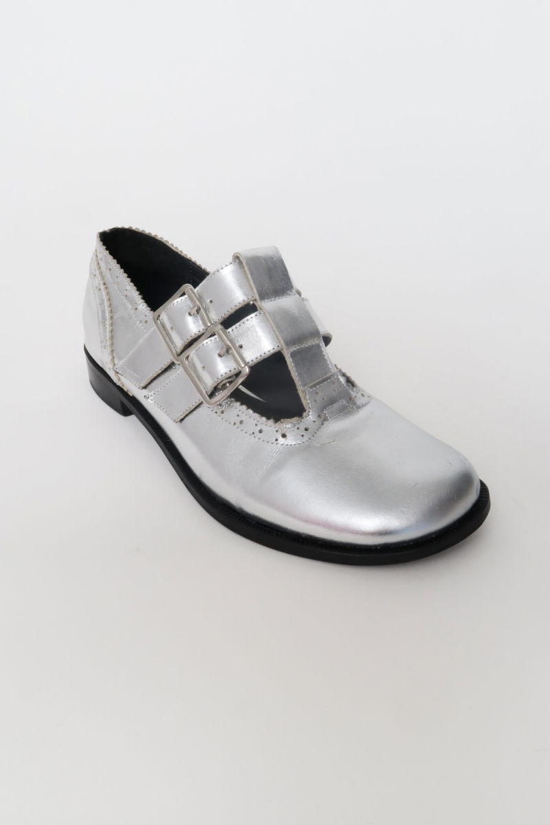 Guillermina de cuero metalizado con punta redonda y taco de 2 cm, con dos tiras ajustables con hebillas metálicas, detalles de zigzag y picado y vira marcada. 