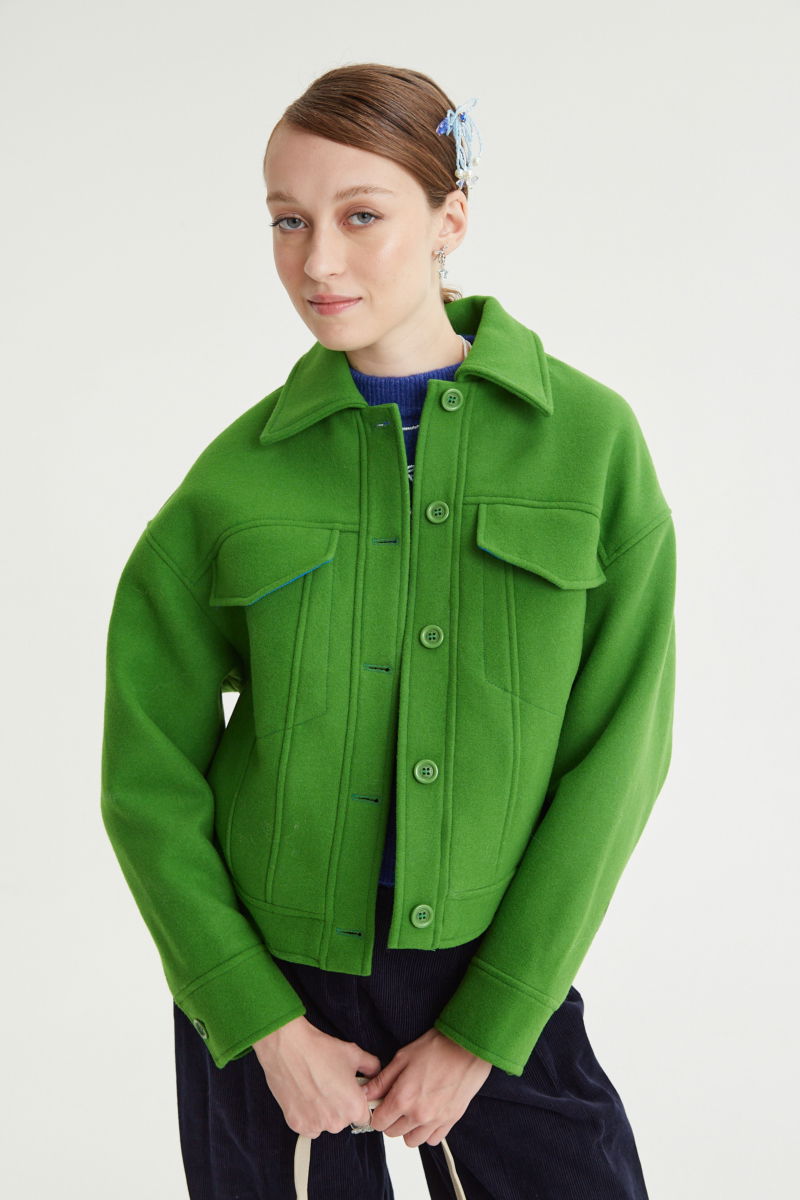 Campera verde de lana recta y larga hasta la cadera con sisas caídas, cuello en punta, botones a tono y bolsillos delanteros con solapa. 