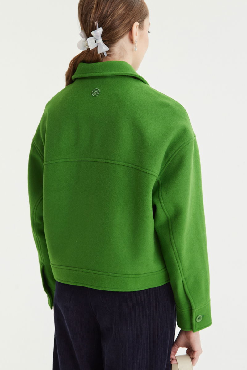 Campera verde de lana recta y larga hasta la cadera con sisas caídas, cuello en punta, botones a tono y bolsillos delanteros con solapa. 