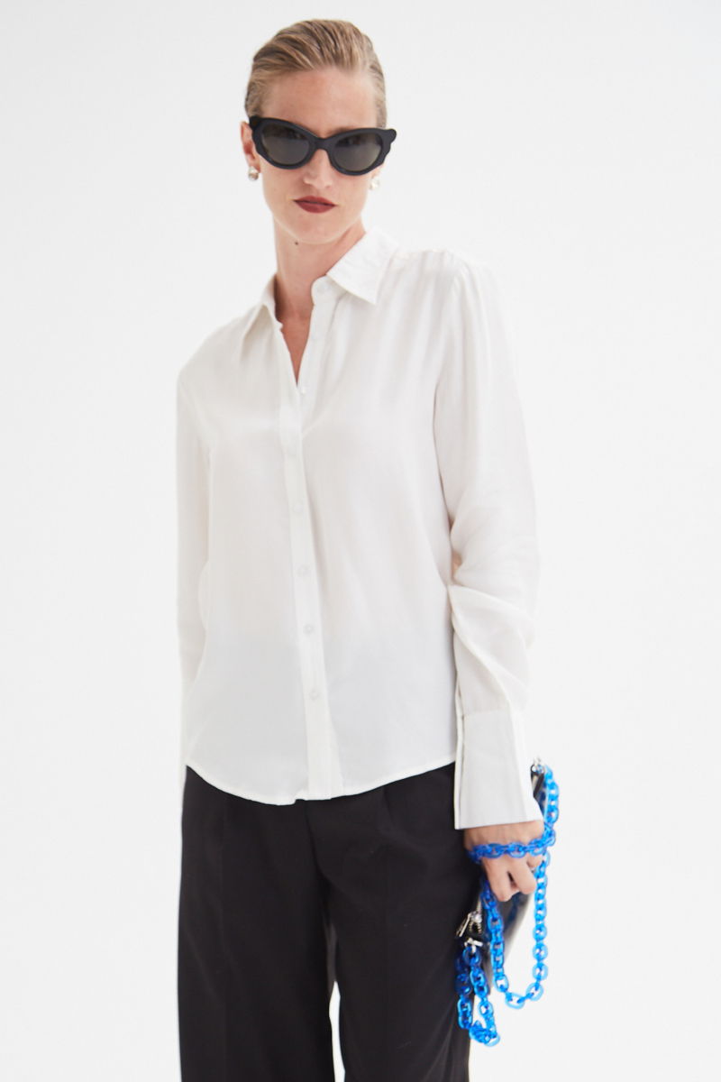 Camisa blanca de calce recto y puños anchos con textura suave de piel de durazno. 
