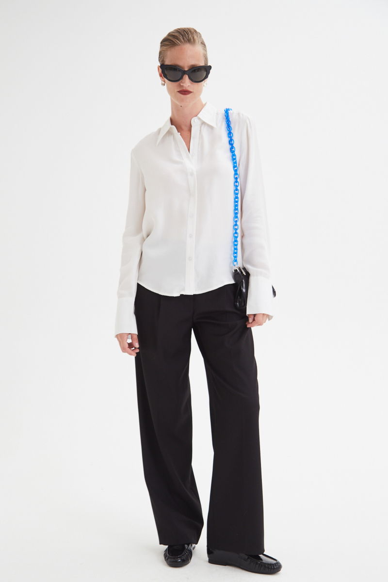 Camisa blanca de calce recto y puños anchos con textura suave de piel de durazno. 
