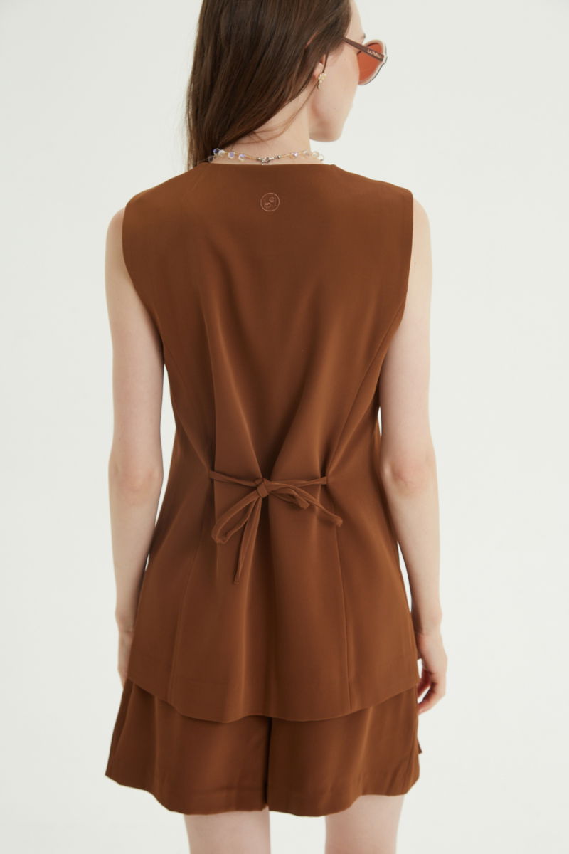 Chaleco sastrero suela con escote en V y largo a la cadera con botones a tono y lazo en la espalda. 