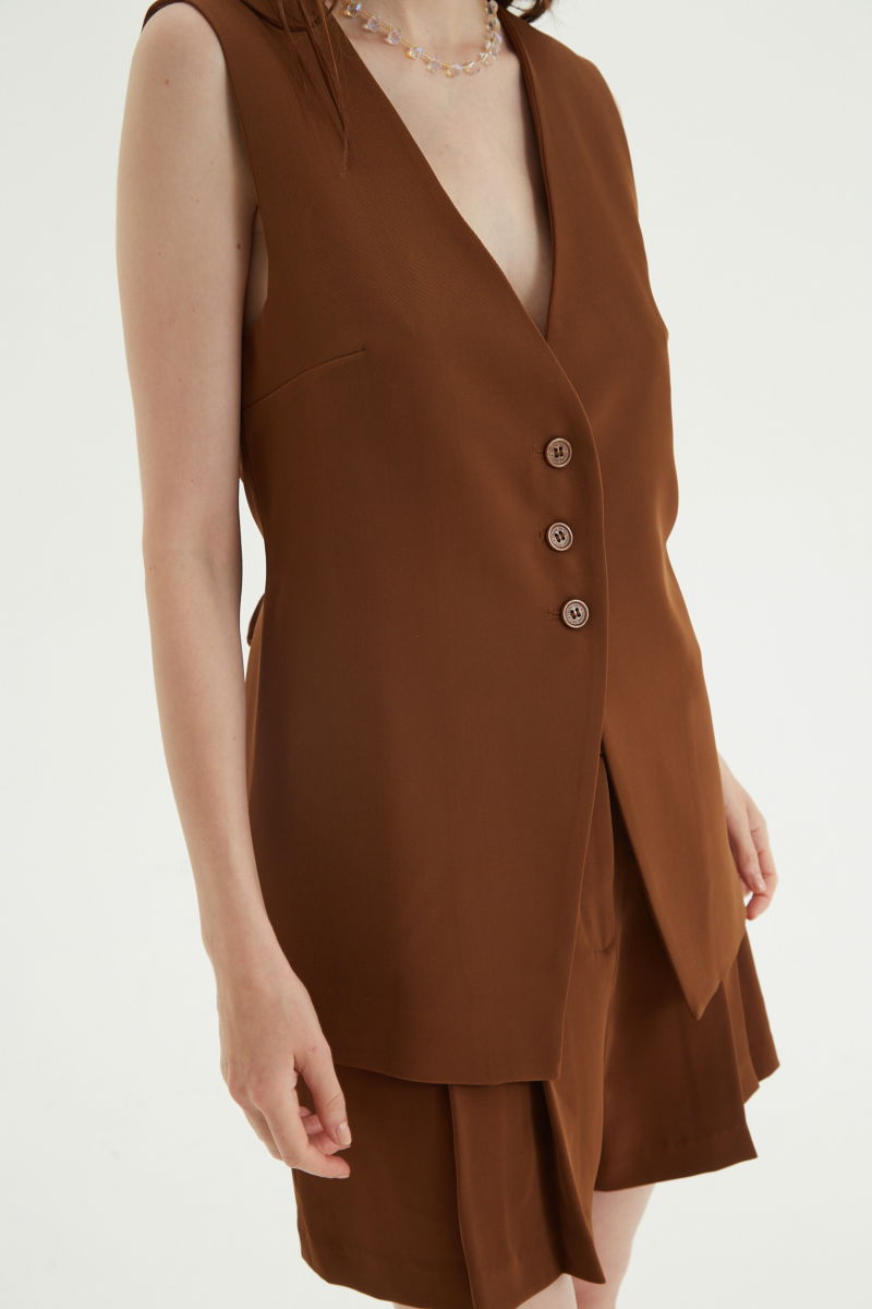 Chaleco sastrero suela con escote en V y largo a la cadera con botones a tono y lazo en la espalda. 