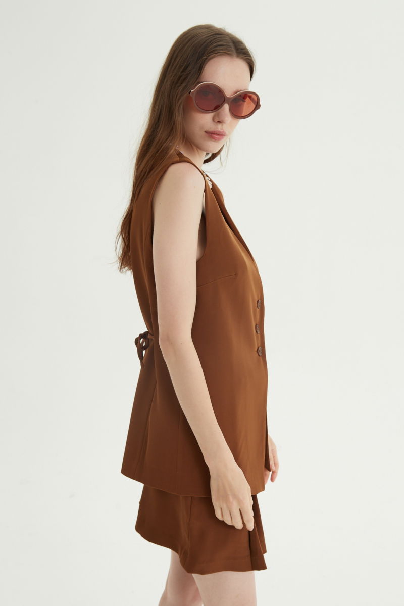 Chaleco sastrero suela con escote en V y largo a la cadera con botones a tono y lazo en la espalda. 