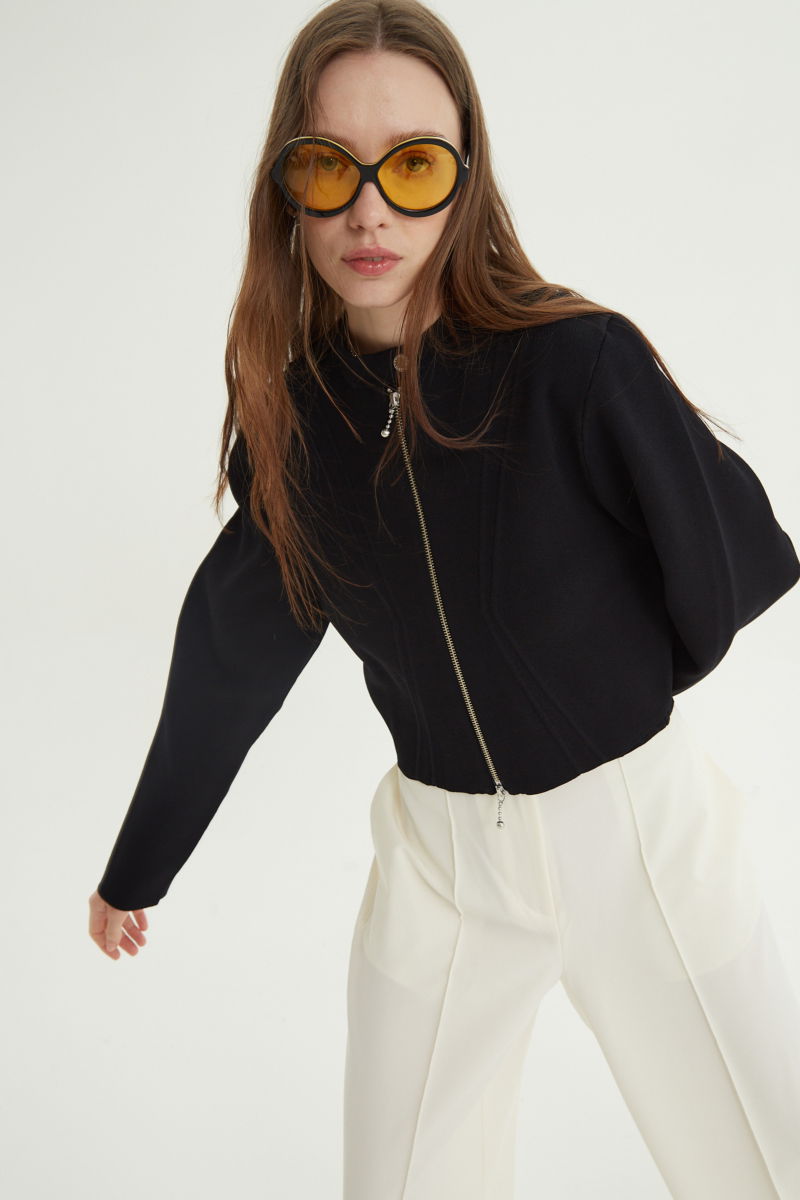 Campera negra tejida estilo bomber larga a la cadera con cierre doble camino, cuello mao con broche snap, hombros anchos y terminación redondeada en el ruedo.