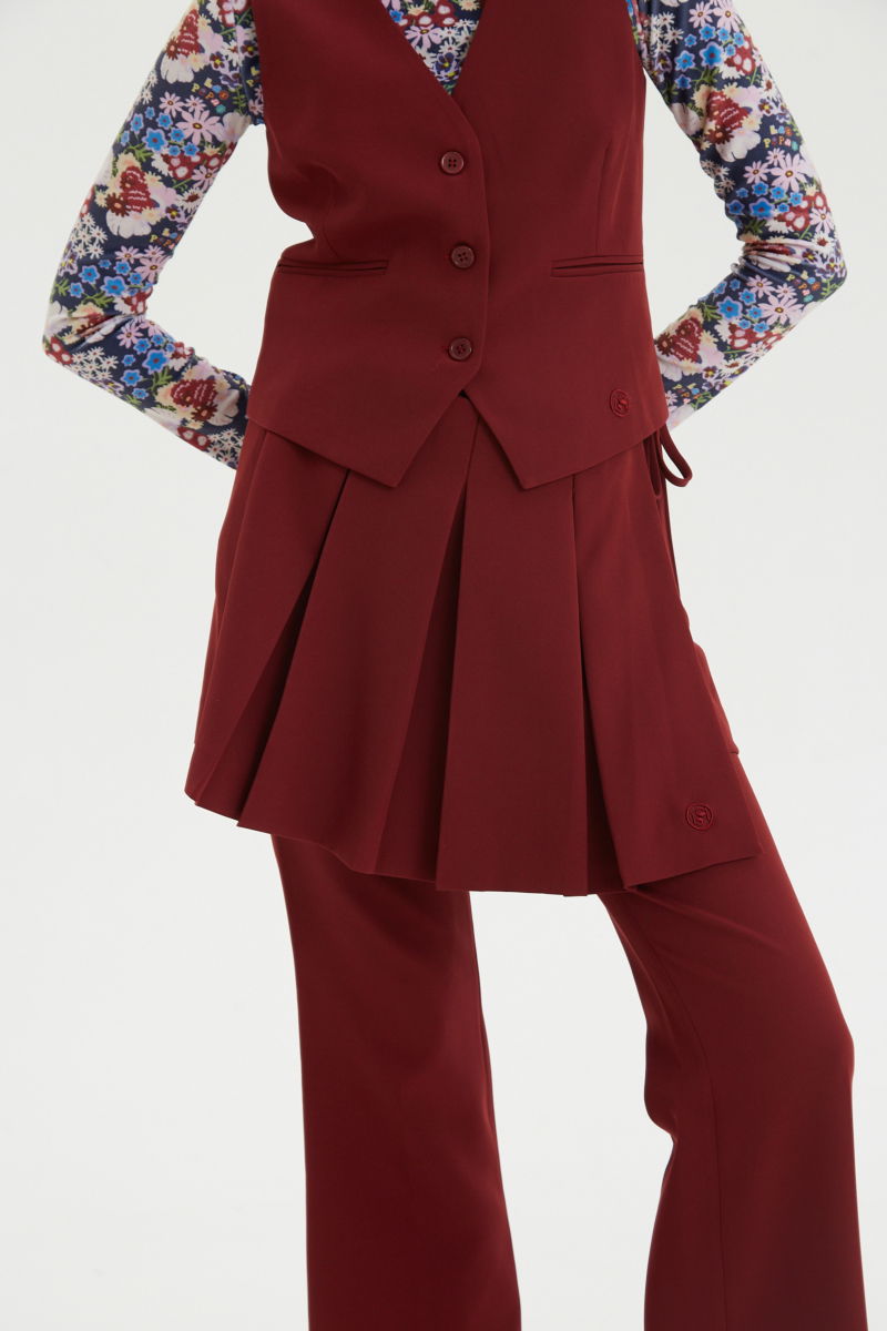 Falda bordo sastrera acampanada con sobre falda tableada con lazo para atar en el lateral. 