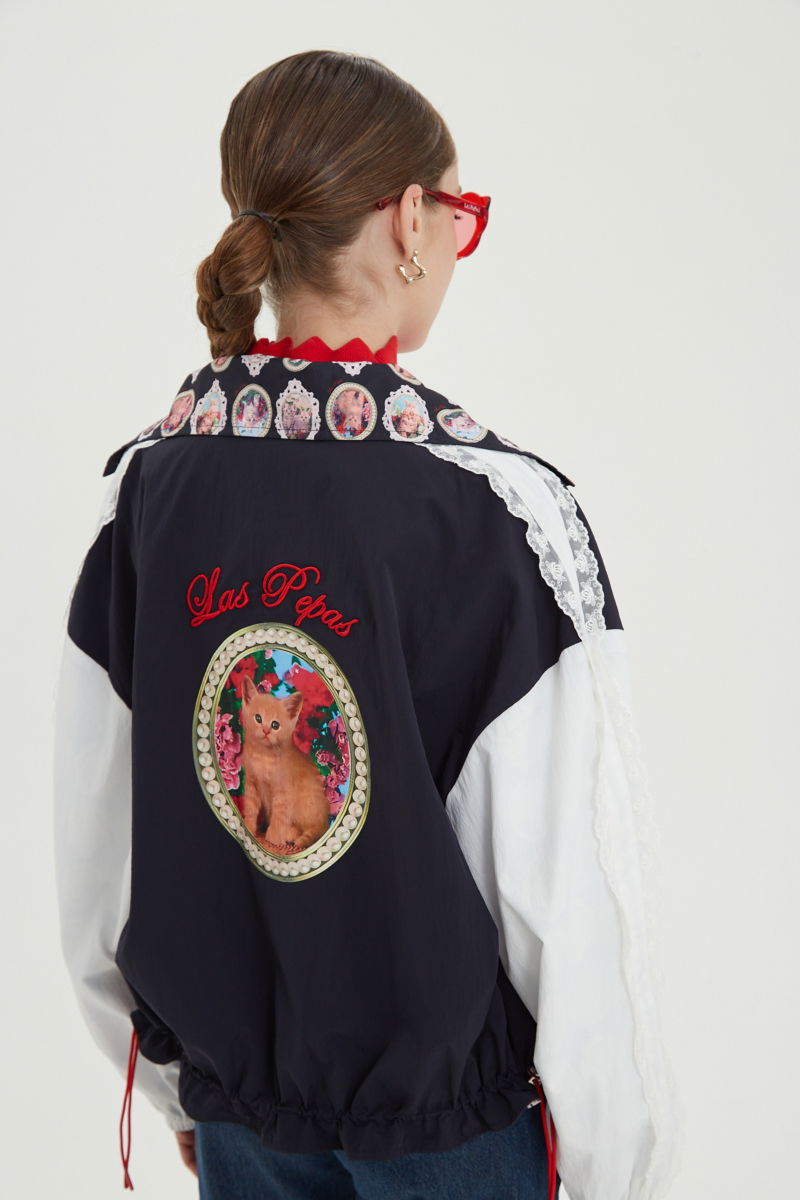 Campera reversible con puntilla y estampado de gatitos, cuello alto, broches snap y cintura con tancas.