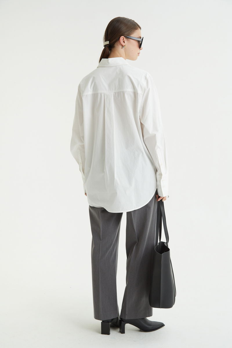 Camisa blanca oversize de poplín de algodón larga por debajo de la cadera con bolsillo aplicado al frente, tabla en la espalda y botones a tono.