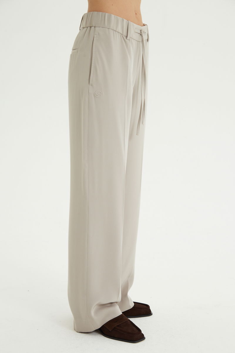 Pantalón beige sastrero tiro alto recto y largo a los tobillos con cintura con elástico y lazo a tono para atar. 