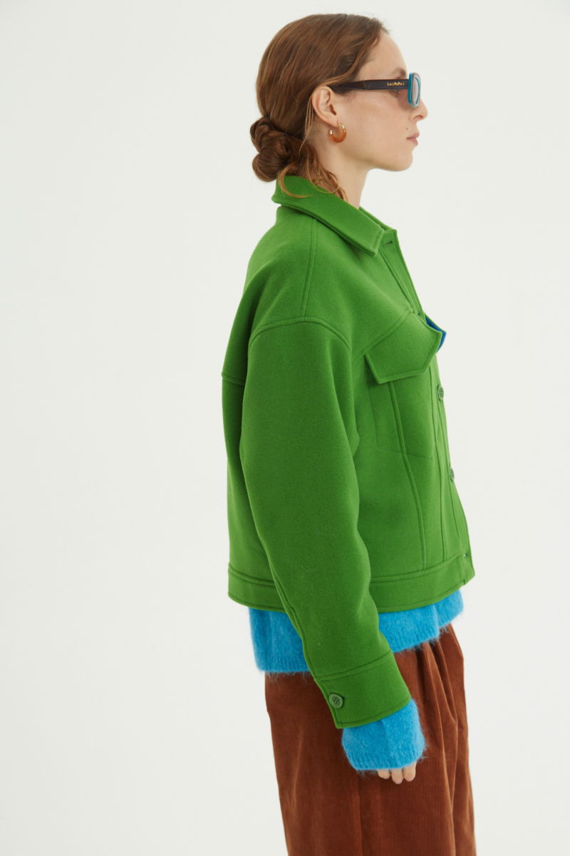 Campera verde de lana recta y larga hasta la cadera con sisas caídas, cuello en punta, botones a tono y bolsillos delanteros con solapa. 