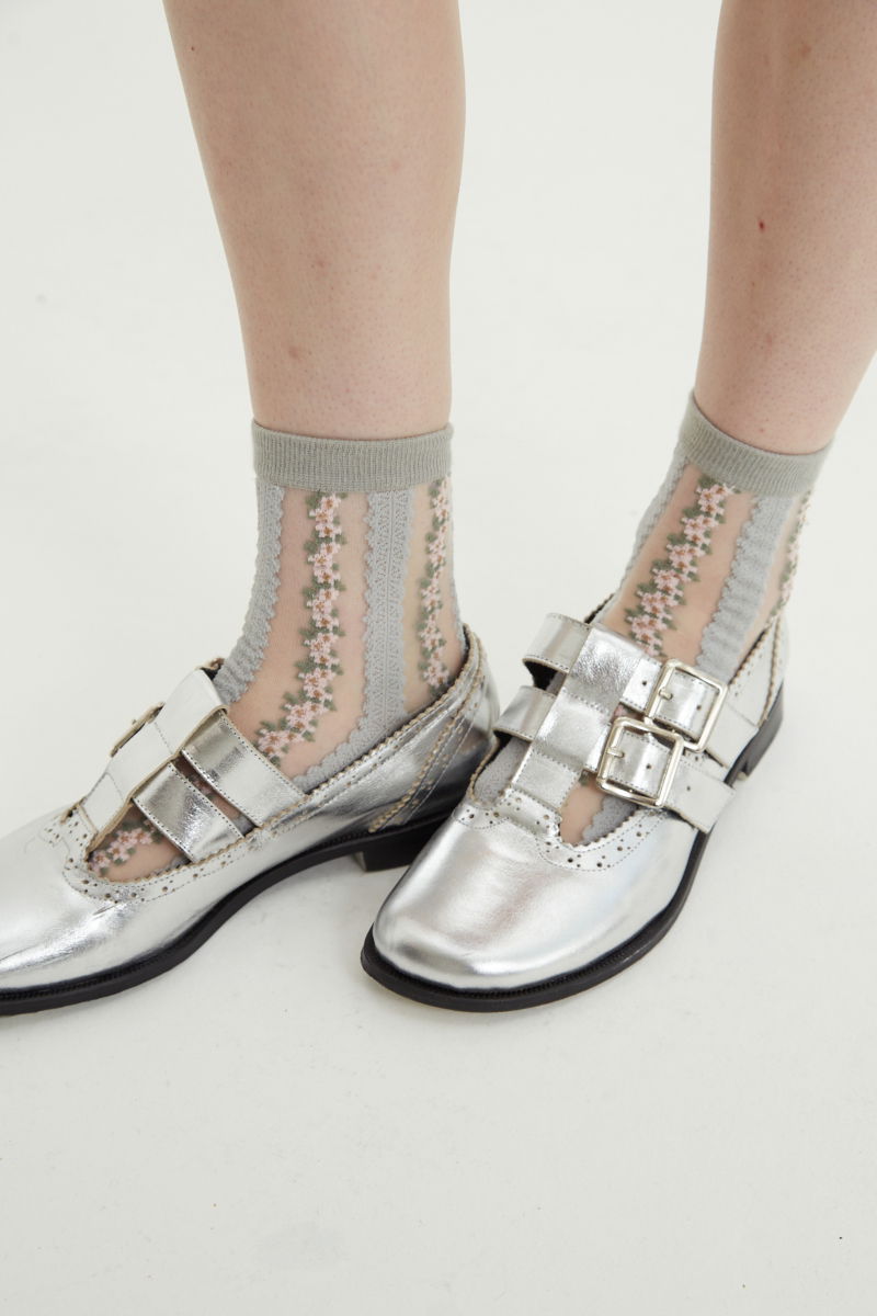 Guillermina de cuero metalizado con punta redonda y taco de 2 cm, con dos tiras ajustables con hebillas metálicas, detalles de zigzag y picado y vira marcada. 