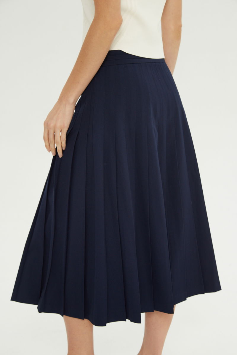 Falda azul sastrera midi de corte evasé y tiro alto con herrajes metálicos en la cintura. 