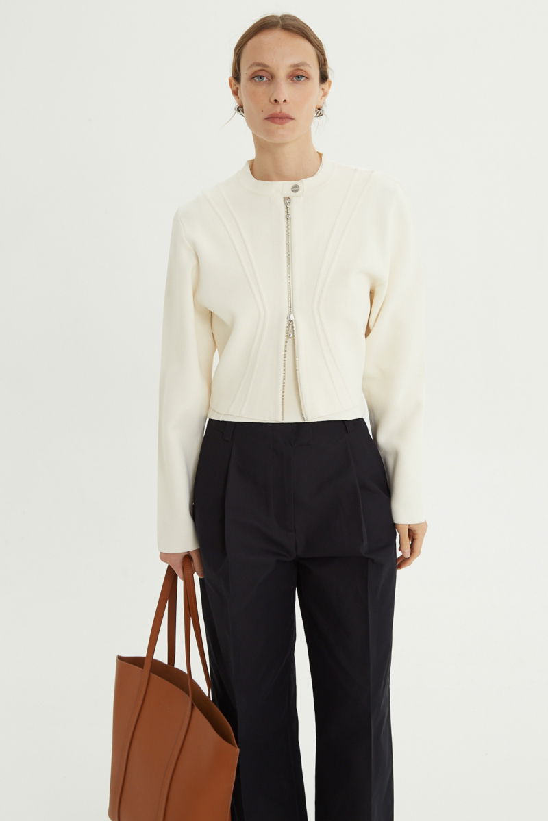 Campera crudo tejida estilo bomber larga a la cadera con cierre doble camino, cuello mao con broche snap, hombros anchos y terminación redondeada en el ruedo.