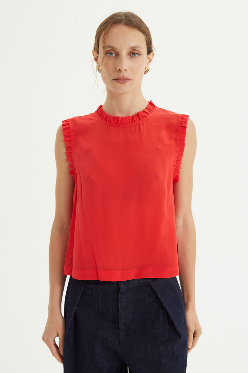 Musculosa roja de seda con volados en cuello y sisas, de corte recto y larga a la cadera con cuello mao y botones en la espalda. 
