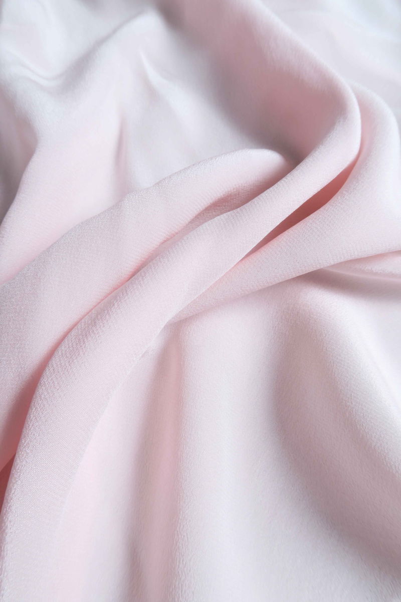 Musculosa rosa de seda con volados en cuello y sisas, de corte recto y larga a la cadera con cuello mao y botones en la espalda. 
