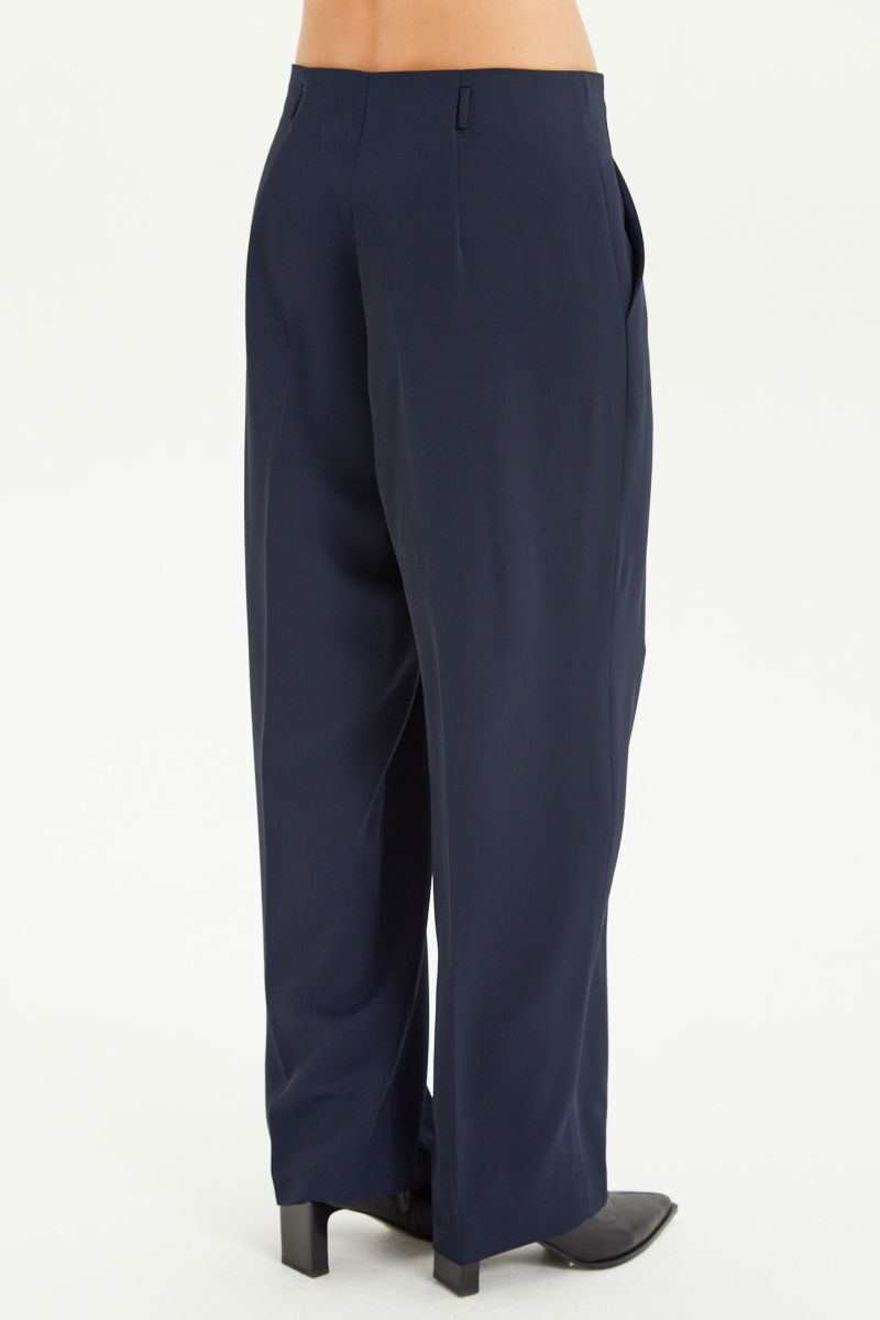 Pantalón azul sastrero tiro alto, de corte recto y largo hasta los tobillos con pinzas de entalle en frente y espalda. 