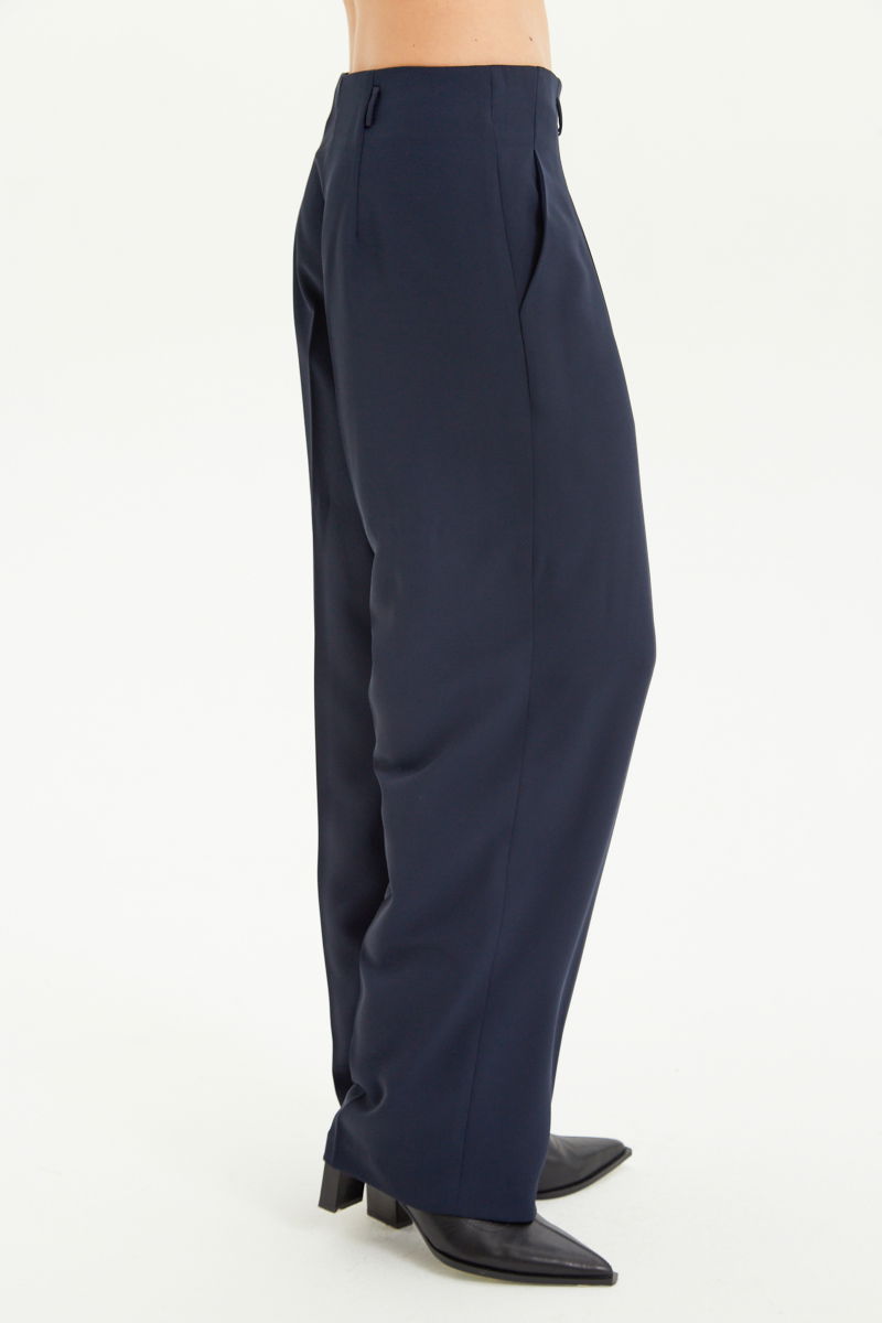 Pantalón azul sastrero tiro alto, de corte recto y largo hasta los tobillos con pinzas de entalle en frente y espalda. 