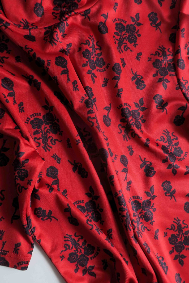 Remera roja entallada y larga a la cadera con cuello semi polera y mangas ¾ con frunces, estampada con print de rosas. 