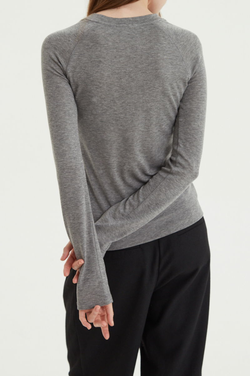 Remera gris manga larga raglán de corte recto y larga a la cadera con cuello redondo y ruedo ancho. 
