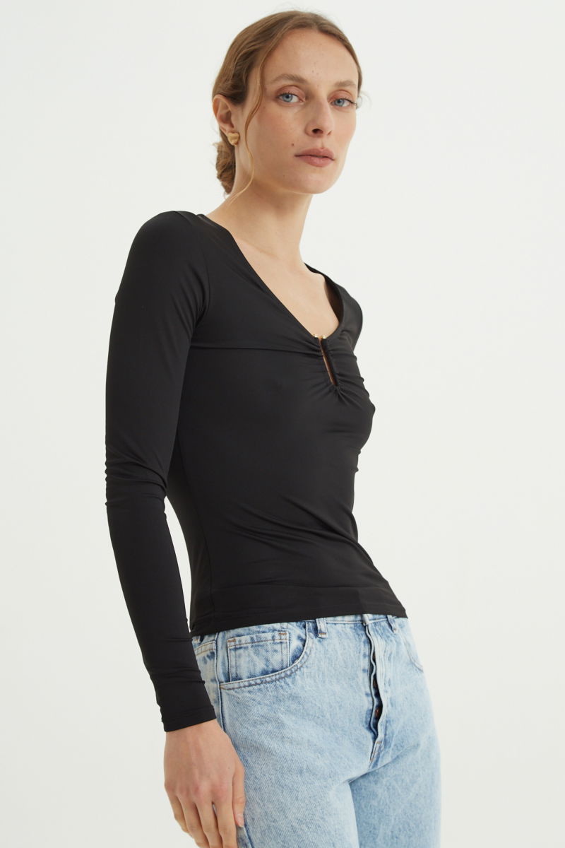 Remera negra manga larga de calce al cuerpo larga a la cadera con escote bajo con avio metalico en forma de U. 
