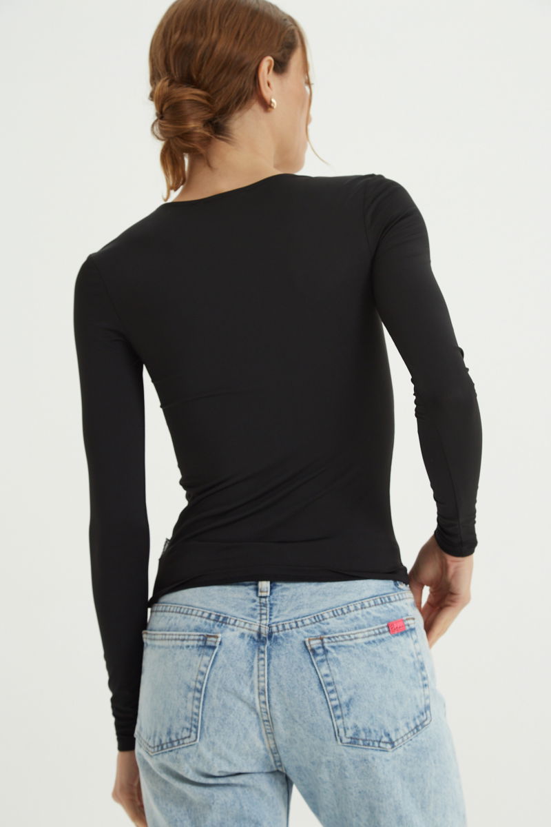 Remera negra manga larga de calce al cuerpo larga a la cadera con escote bajo con avio metalico en forma de U. 
