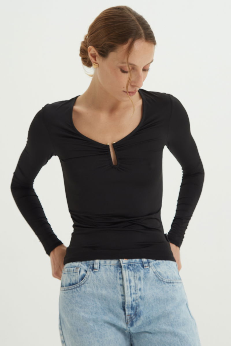 Remera negra manga larga de calce al cuerpo larga a la cadera con escote bajo con avio metalico en forma de U. 
