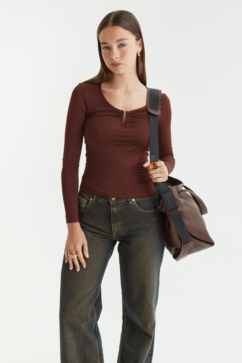 Remera marron manga larga de calce al cuerpo larga a la cadera con escote bajo con avio metalico en forma de U. 
