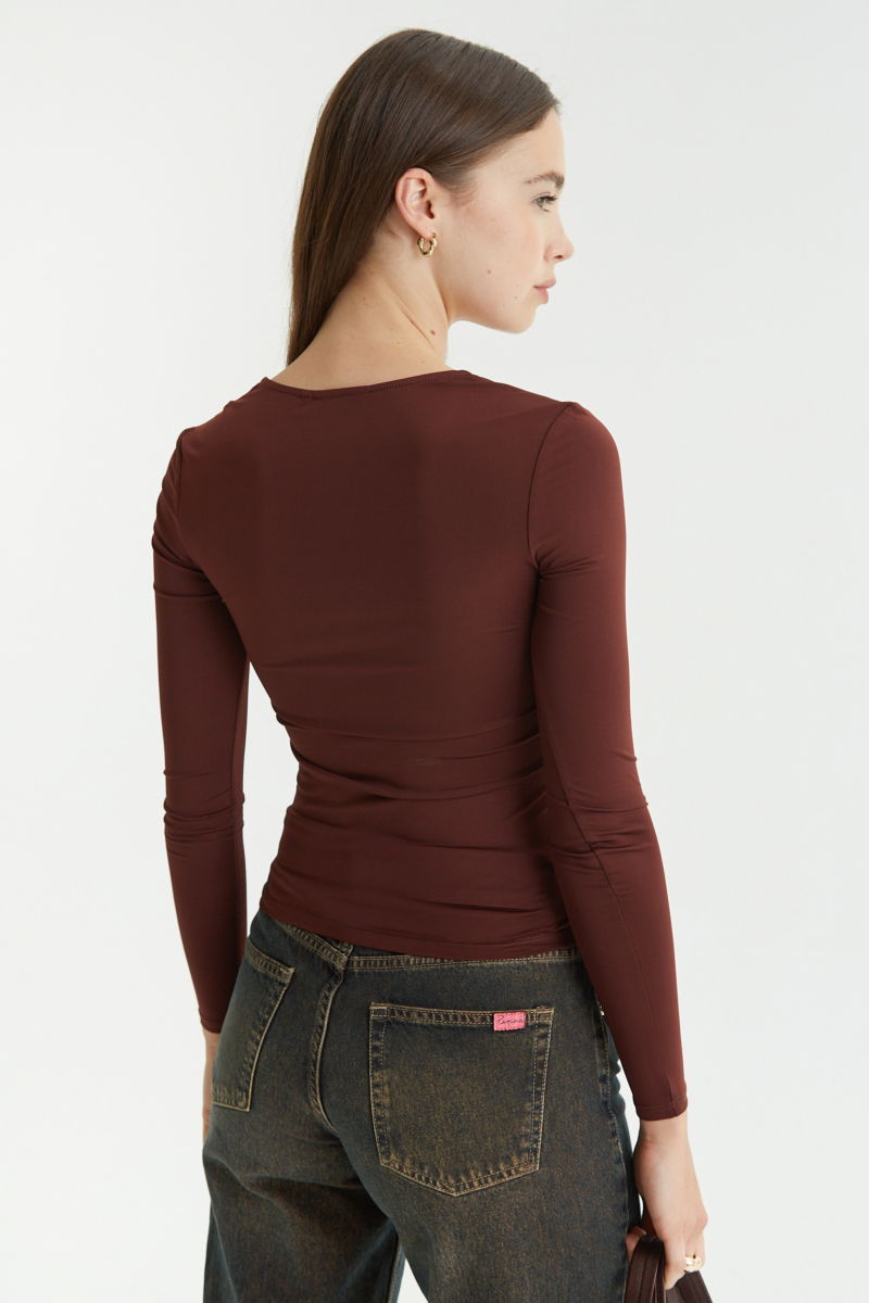 Remera marron manga larga de calce al cuerpo larga a la cadera con escote bajo con avio metalico en forma de U. 
