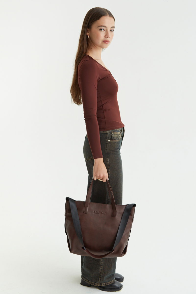 Remera marron manga larga de calce al cuerpo larga a la cadera con escote bajo con avio metalico en forma de U. 
