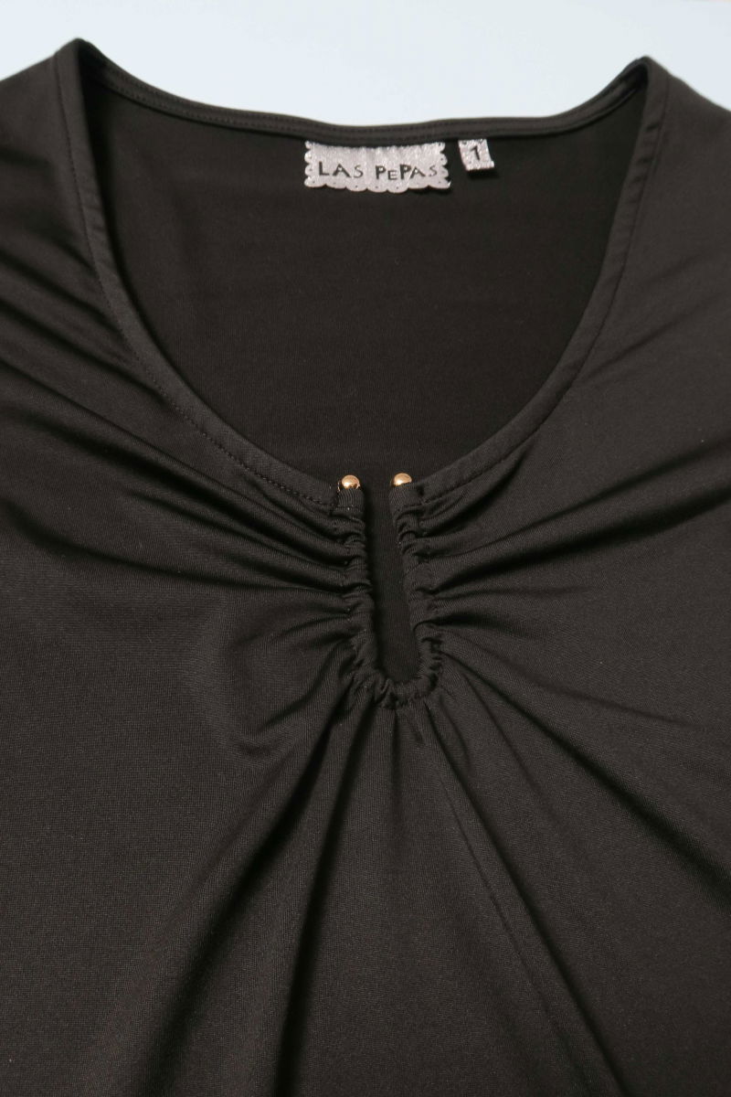 Remera negra manga larga de calce al cuerpo larga a la cadera con escote bajo con avio metalico en forma de U. 
