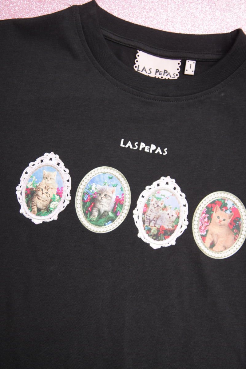 Remera negra suelta y crop de algodón estampada con lazos en las mangas para atar en moño.
