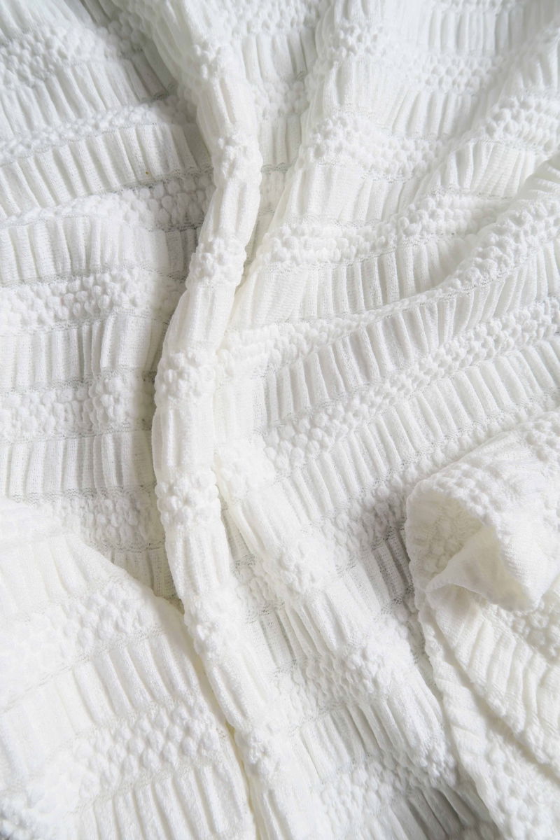 Remera blanca al cuerpo con mangas semi acampanadas, con escote a la base del cuello y textura fruncida. 
