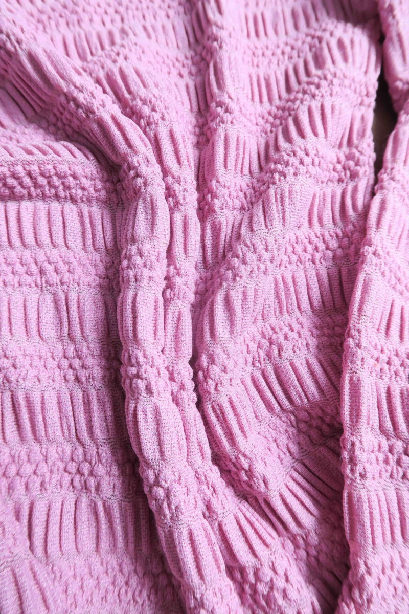 Remera rosa al cuerpo con mangas semi acampanadas, con escote a la base del cuello y textura fruncida. 
