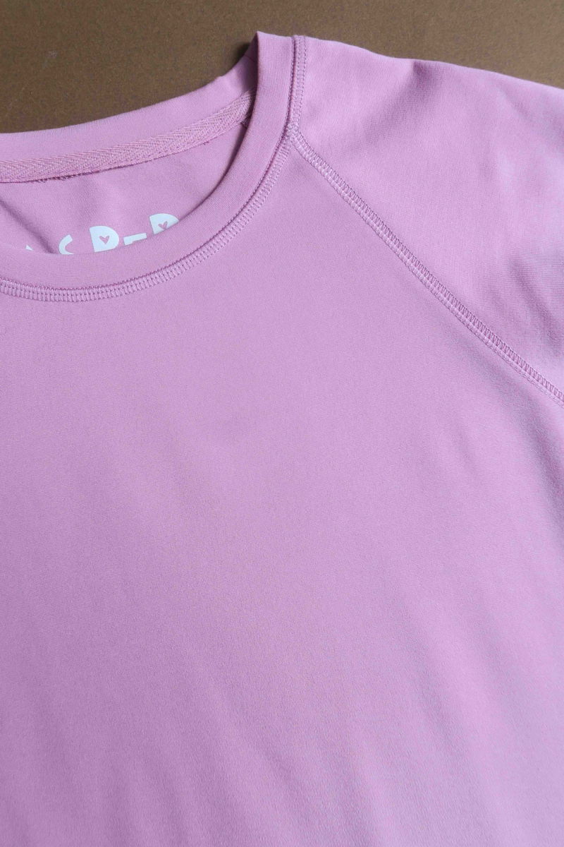 Remera rosa básica al cuerpo larga a la cadera con escote redondo y mangas cortas raglan. 
