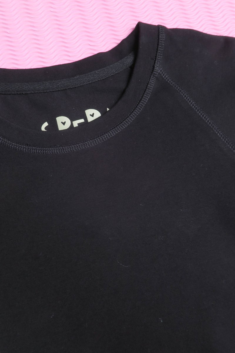 Remera negra básica al cuerpo larga a la cadera con escote redondo y mangas cortas raglan. 
