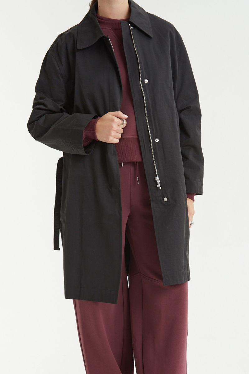 Saco negro liviano recto y largo por arriba de las rodillas con cierre, broches snap y cinturon. 
