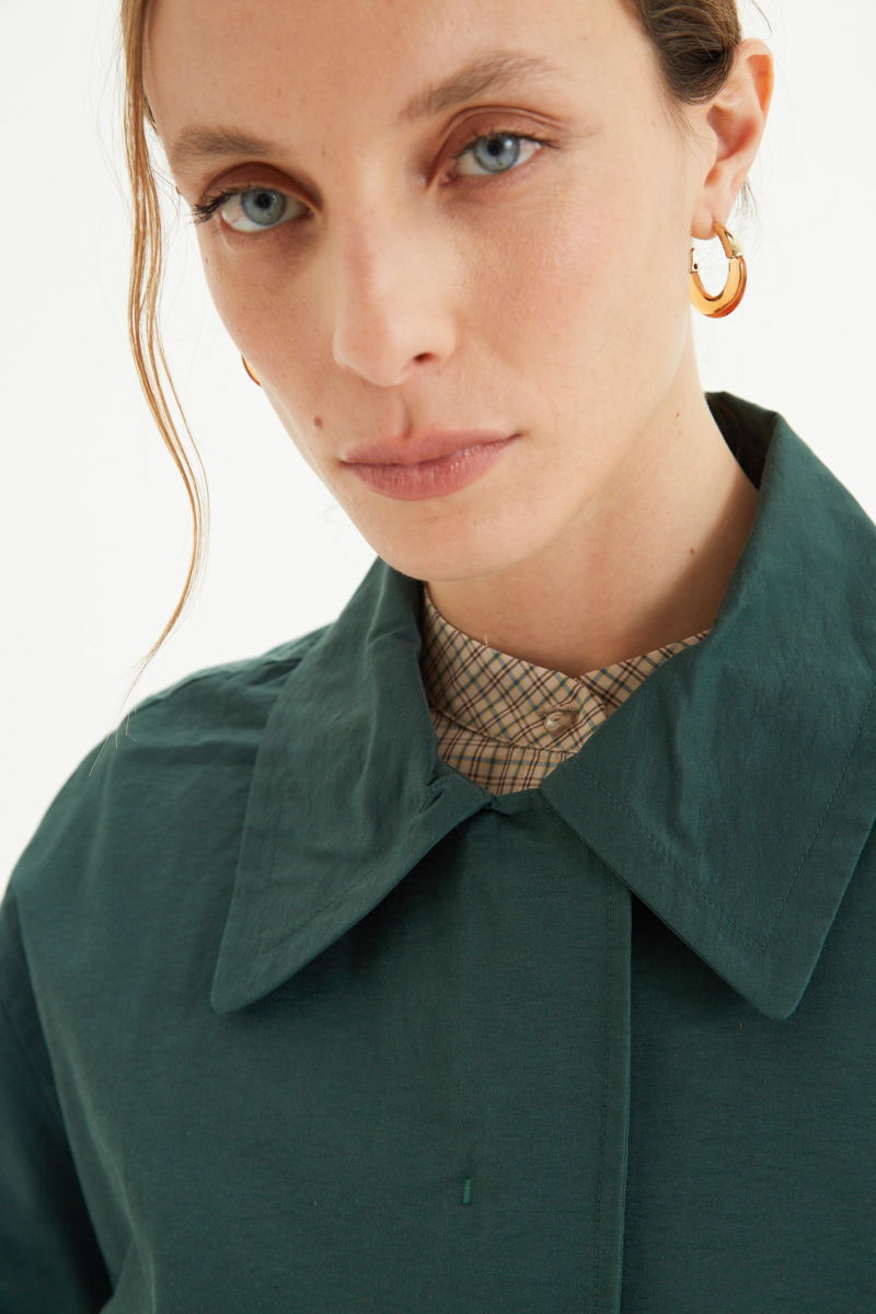 Saco verde liviano recto y largo por arriba de las rodillas con cierre, broches snap y cinturon. 
