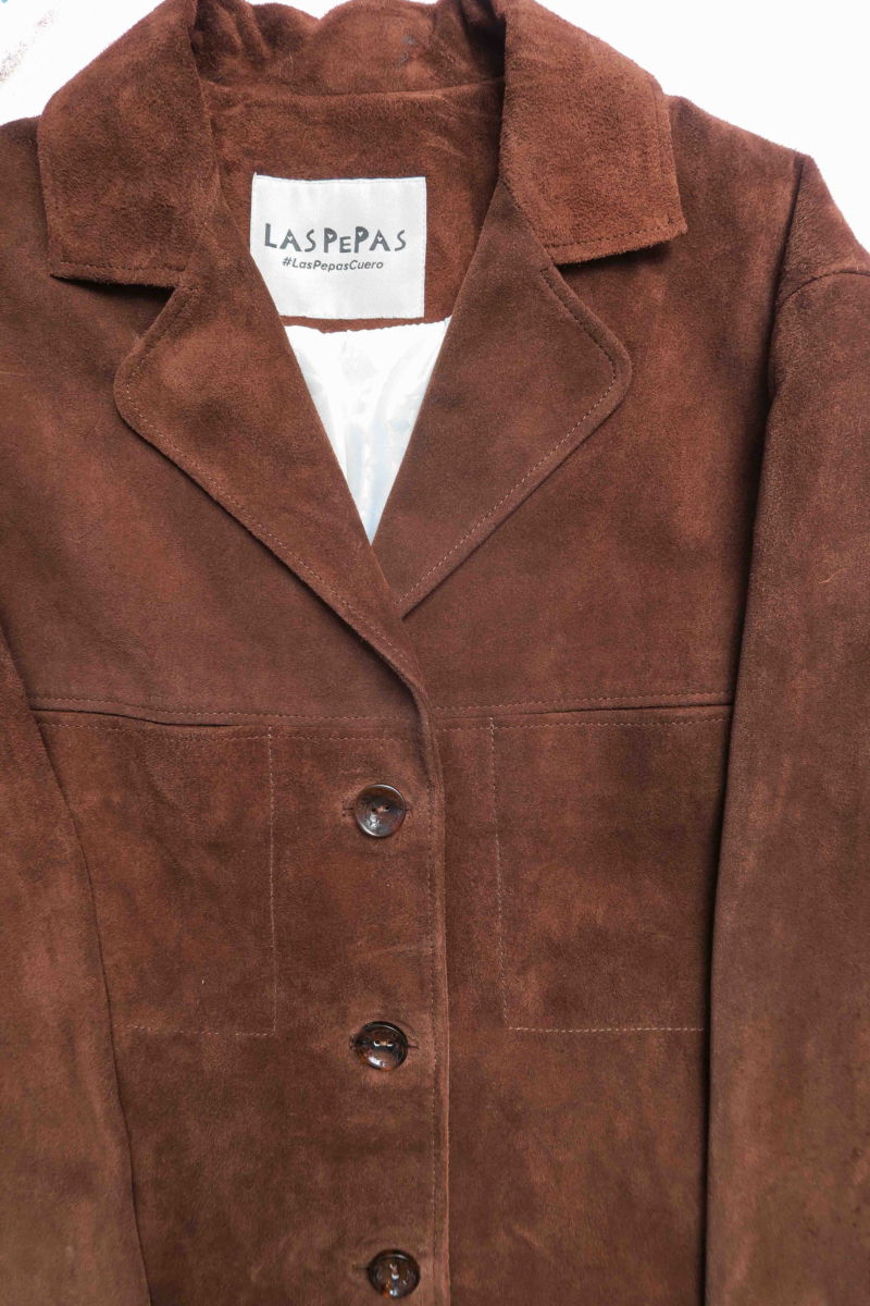 Saco oversize de gamuza largo debajo de la cadera con botones nacarados, bolsillos frontales y laterales y recortes. 
