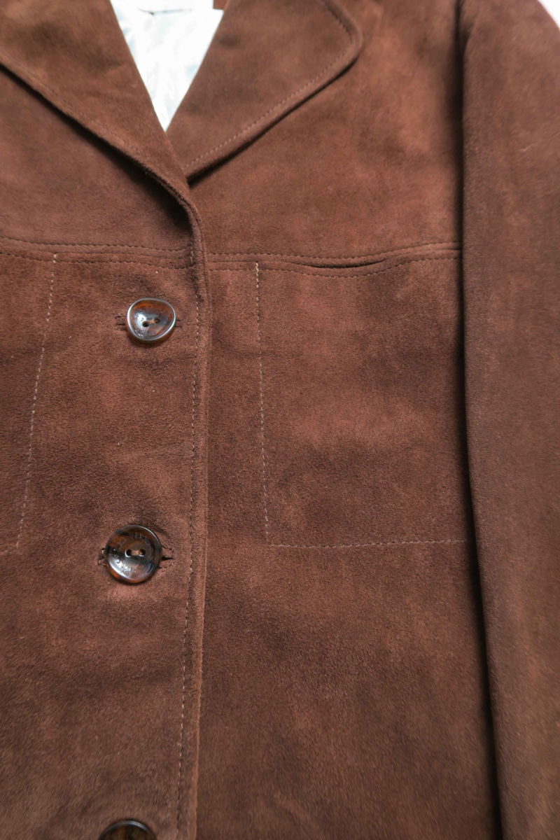 Saco oversize de gamuza largo debajo de la cadera con botones nacarados, bolsillos frontales y laterales y recortes. 
